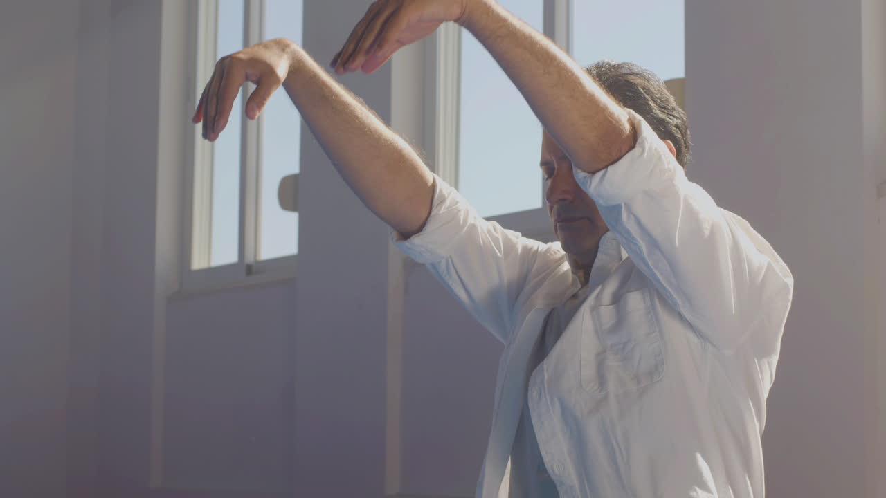 hombre enfocado moviendo las manos mientras está sentado en el suelo en el gimnasio