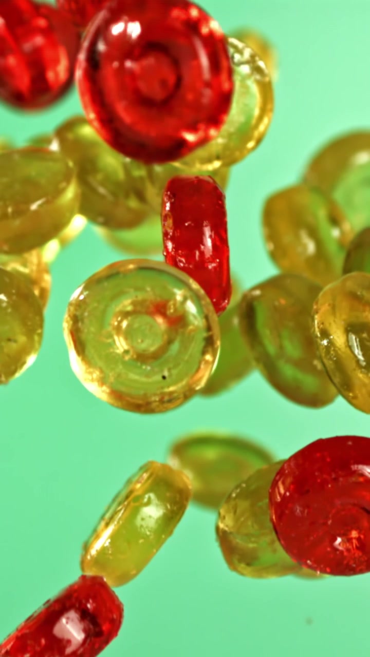 Caramelle colorate che cadono al rallentatore su sfondo verde