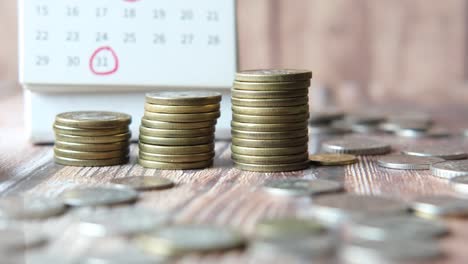 stack of coins and calendar on wooden background