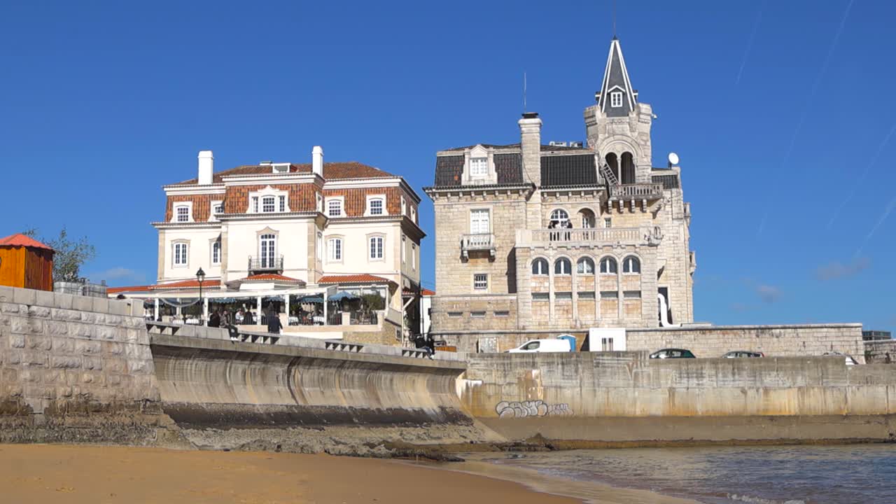 Vista soleada de la playa del Palacio de Seixas en Cascais, mostrando torres históricas y una arquitectura elegante a lo largo de la costa atlántica