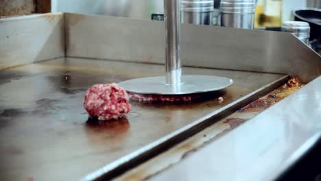 4K-Cinematic-food-cooking-footage-of-a-chef-preparing-and-making-a-delicious-homemade-burger-in-a-restaurant-kitchen-in-slow-motion-by-smashing-the-beef-into-a-smashed-burger-patty-on-the-grill