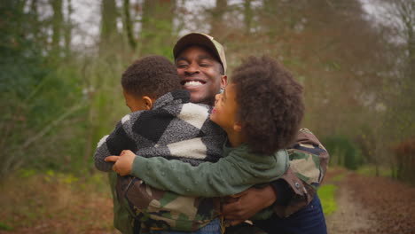 american soldier in uniform returning home to family on hugging children outside house