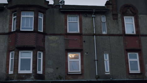 Edificios-De-Apartamentos-Con-Carcasa-De-Tubería-Asegurada-Contra-El-Borde-Del-Edificio,-Habitación-Con-Ventana-única-Iluminada