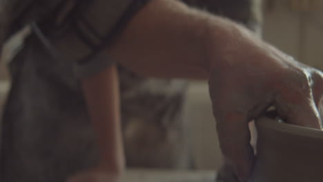 senior potter shaping clay bowl on wheel