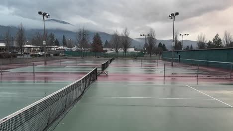 rain clouds pass over a wet tennis court in oregon