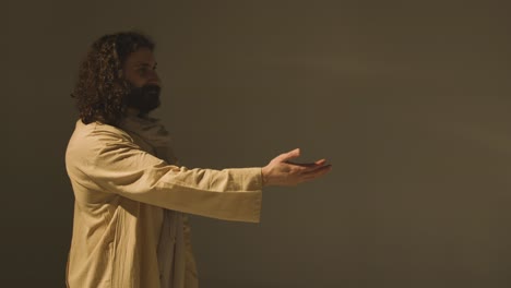 hombre con túnicas de pelo largo y barba que representa la figura de jesucristo ofreciendo una mano de ayuda