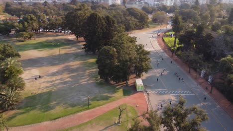 gente activa caminando o trotando en la carretera en el parque al lado del lago de palermo durante la puesta de sol