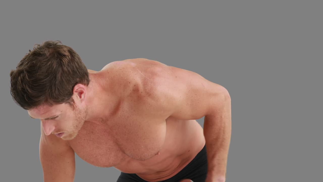 심각한 근육 남자가 덤벨을 들어 올리고 있습니다.