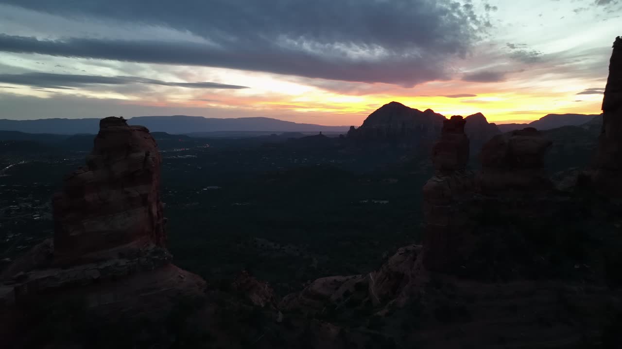 Flyver gennem klippesøjler mod en dramatisk solnedgangshimmel i Sedona, Arizona