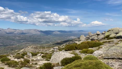 Filmando-Desde-La-Cima-De-Una-Montaña-Donde-Visualizamos-El-Espectacular-Valle-Del-Alberche-Y-Al-Girar-La-Cámara-Hay-Agrupaciones-De-Llamativas-Rocas-De-Granito,-Al-Fondo-Hay-Un-Pico-Formado-Por-Rocas