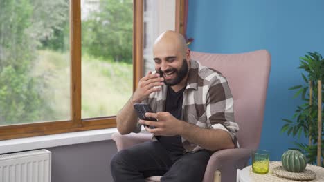 Man-smiling-at-phone-message.