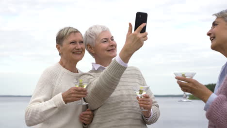 tres encantadoras mujeres serias bailando y tomándose selfies mientras toman una copa 1