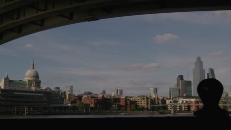 the view of saint paul cathedral and surrounding buildings from under a bridge in london