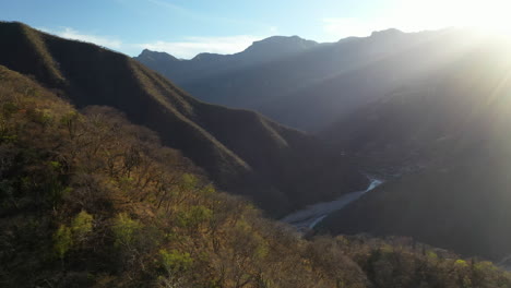 sun setting behind mountain landscape of copper canyon, mexico, aerial