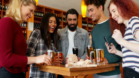 group of fiends playing jenga while having beer 4k