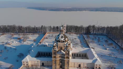 Aerial-view-of-the-Pazaislis-monastery-and-the-Church-of-the-Visitation-in-Kaunas,-Lithuania-in-winter,-snowy-landscape,-Italian-Baroque-architecture,-flying-around-the-tower,-crane-shot