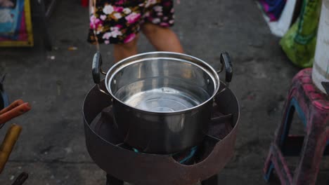 cocinero tailandés poniendo sal y verduras en una olla para hacer sopa de tom yam