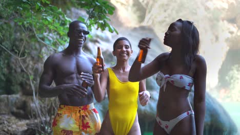 multiracial friends with beer dancing near lake