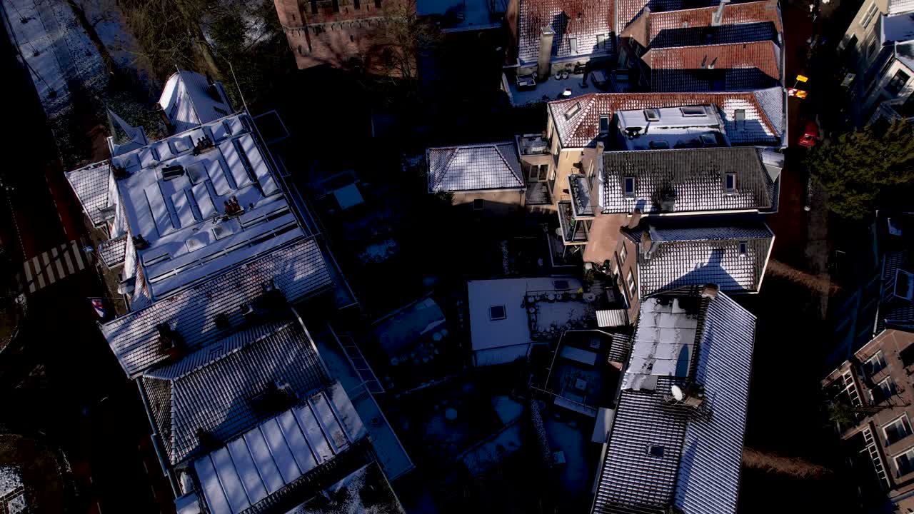 Top down winter wonderland rooftops covered in snow with aerial reveal of Drogenapstoren and historic Hanseatic Dutch tower town Zutphen in The Netherlands with Walburgiskerk cathedral in the back