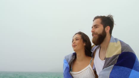 vista frontal de una pareja caucásica en manta caminando por la playa 4k