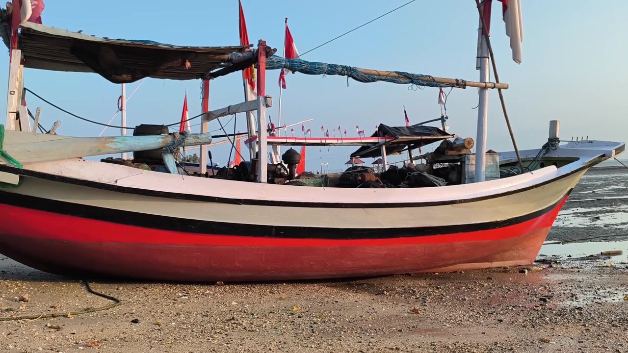 Barca da pesca tradizionale adagiata su una spiaggia sabbiosa con la bassa marea