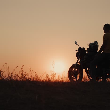 Die-Silhouette-Eines-Mannes-Auf-Einem-Motorrad,-Der-Den-Sonnenuntergang-Bewundert