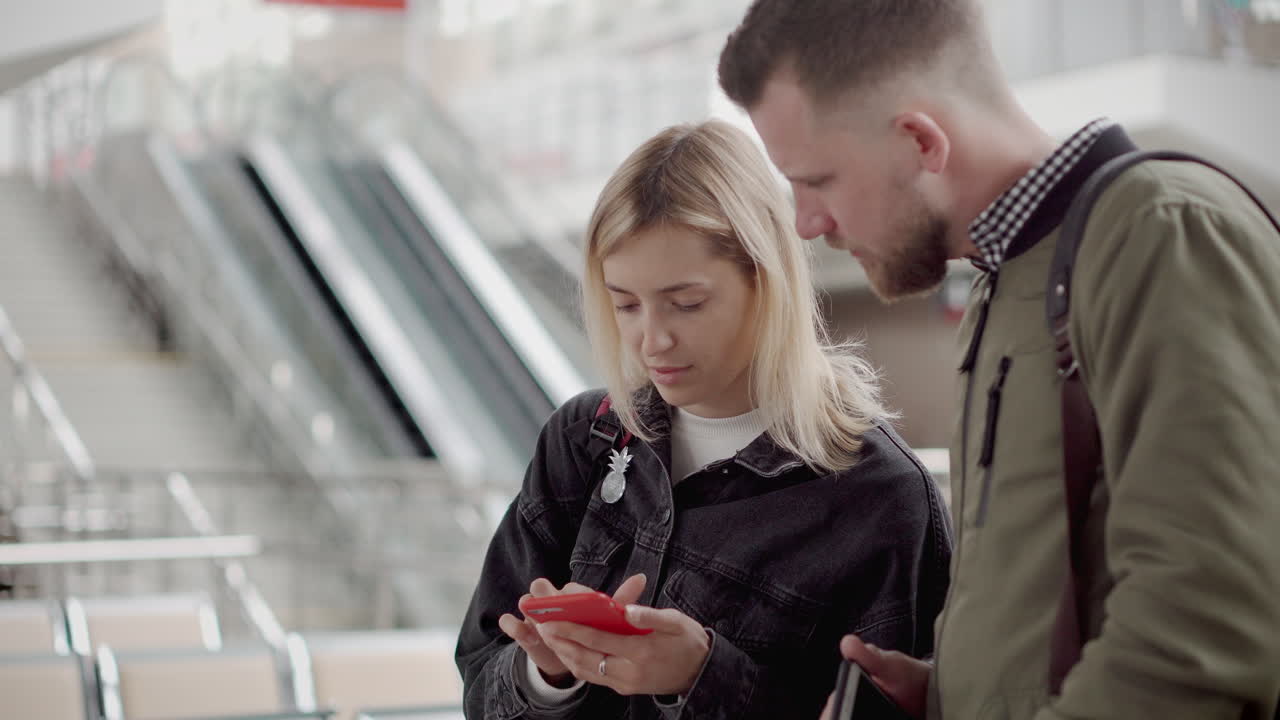 пара смотрит на телефон на железнодорожном вокзале
