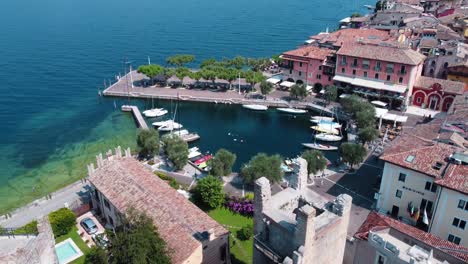 flying over the castle of torri del benaco and revealing a picturesque harbor at lake garda