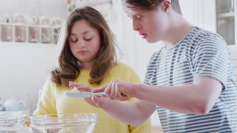 Una-Pareja-Joven-Con-Síndrome-De-Down-Agrega-Mantequilla-A-La-Receta-Del-Pastel-Que-Están-Horneando-En-La-Cocina-De-Casa