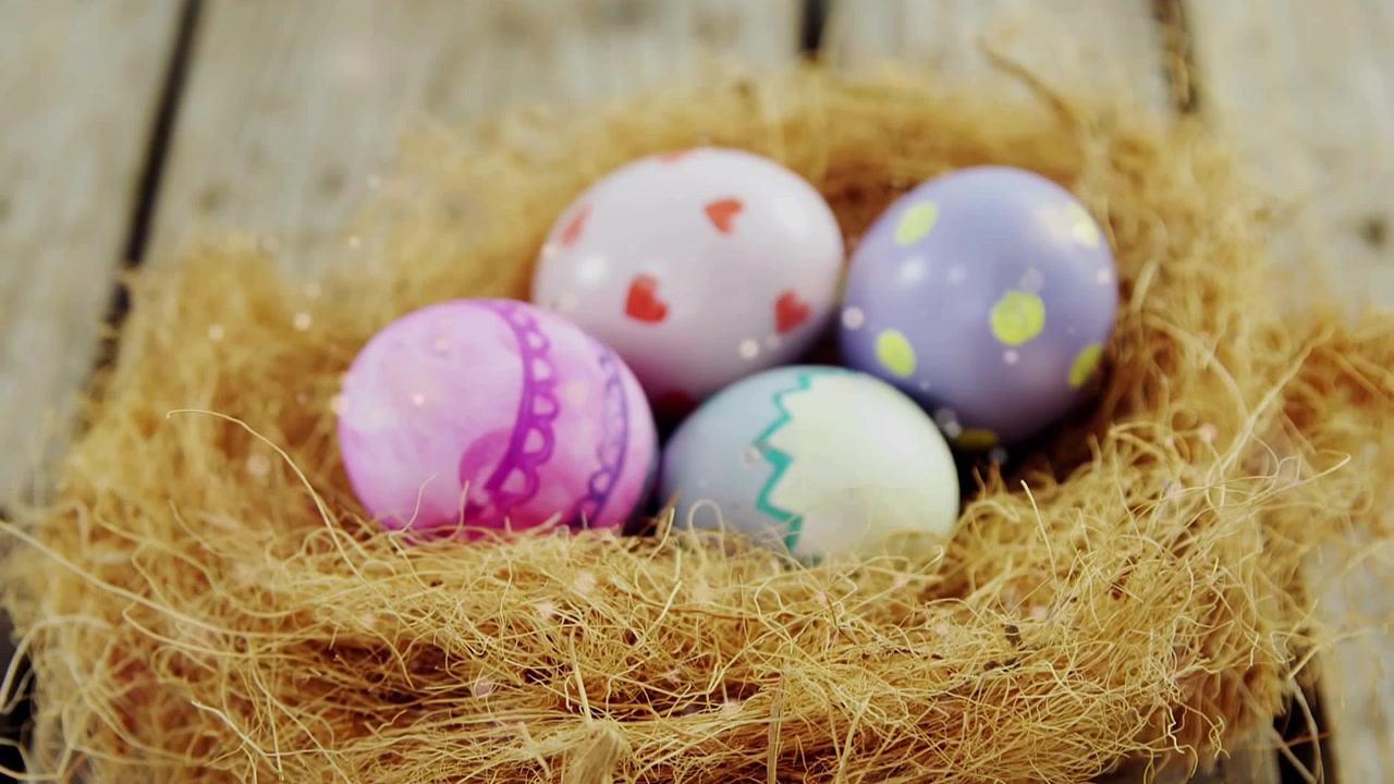 Camera pulling back, revealing straw nest with four pastel eggs, sparkles drifting for Easter ad
