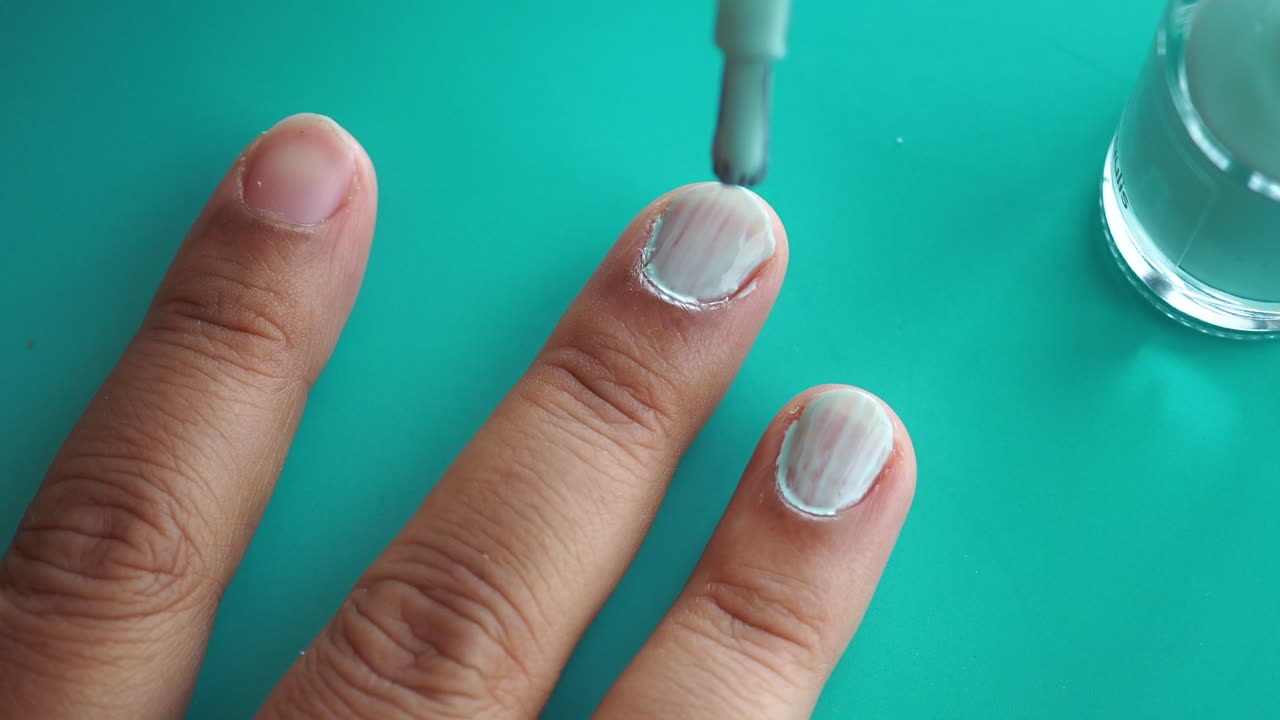 mujer aplicando esmalte de uñas azul claro