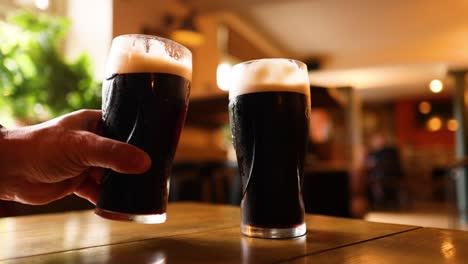 cheers! two glasses of dark beer in a pub