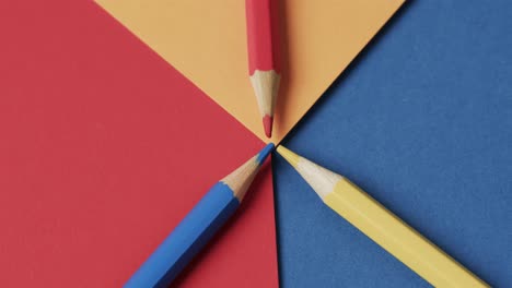 overhead view of crayons on colourful background, in slow motion