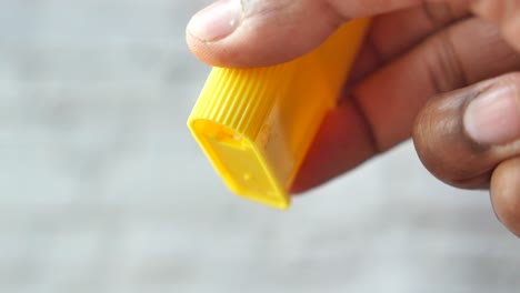 hand holding yellow plastic container