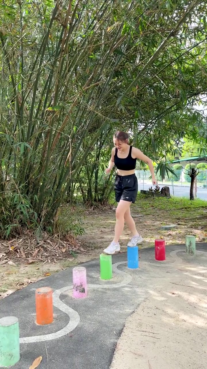 Una joven tailandesa se equilibra sobre coloridas piedras de equilibrio durante una sesión de ejercicio en un parque al aire libre