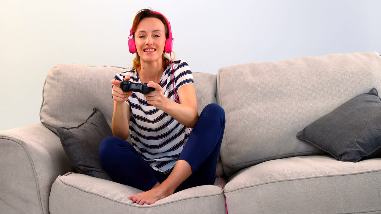 donna con cuffie che gioca a joystick sul divano 4k
