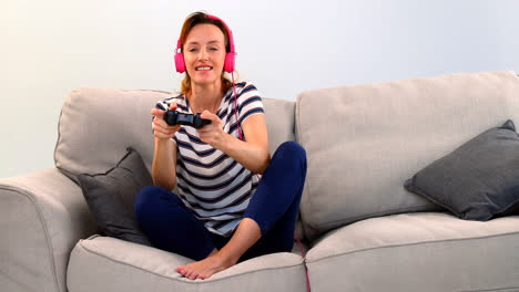 mujer con auriculares jugando un juego de joystick en el sofá 4k