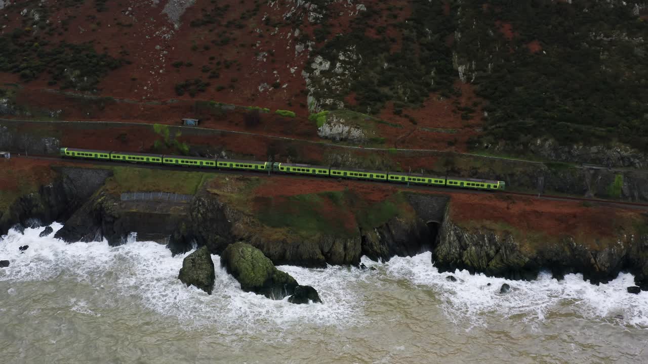 Wide Aerial View of Following the Irish Rail DART Along the Dramatic Bray Head Coast With Waves Crashing Below