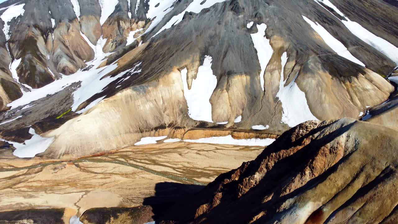 The aerial reveal of a gorge and colourful mountain slopes covered with patches of snow