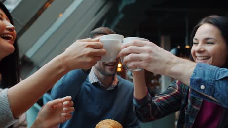 movimiento lento de amigos felices hombres y mujeres celebrando el evento en el café sonando tazas de café riendo