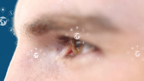 animation of icons over eye of caucasian man on blue background