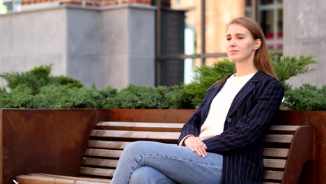 young business woman sitting outside office and looking around