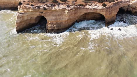 Caves-in-Benagil-coast-in-Algarve,-Portugal---Tilt-up-Reveal-Aerial-shot