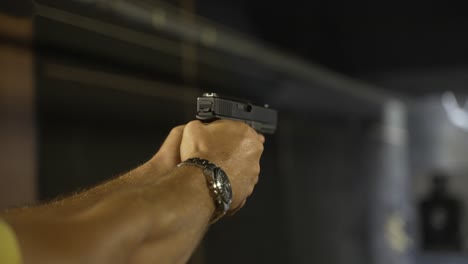 Closeup of a man firing a gun showing his concentration as he aims at the target and fires as a muzzle flash comes out of the gun after the shot