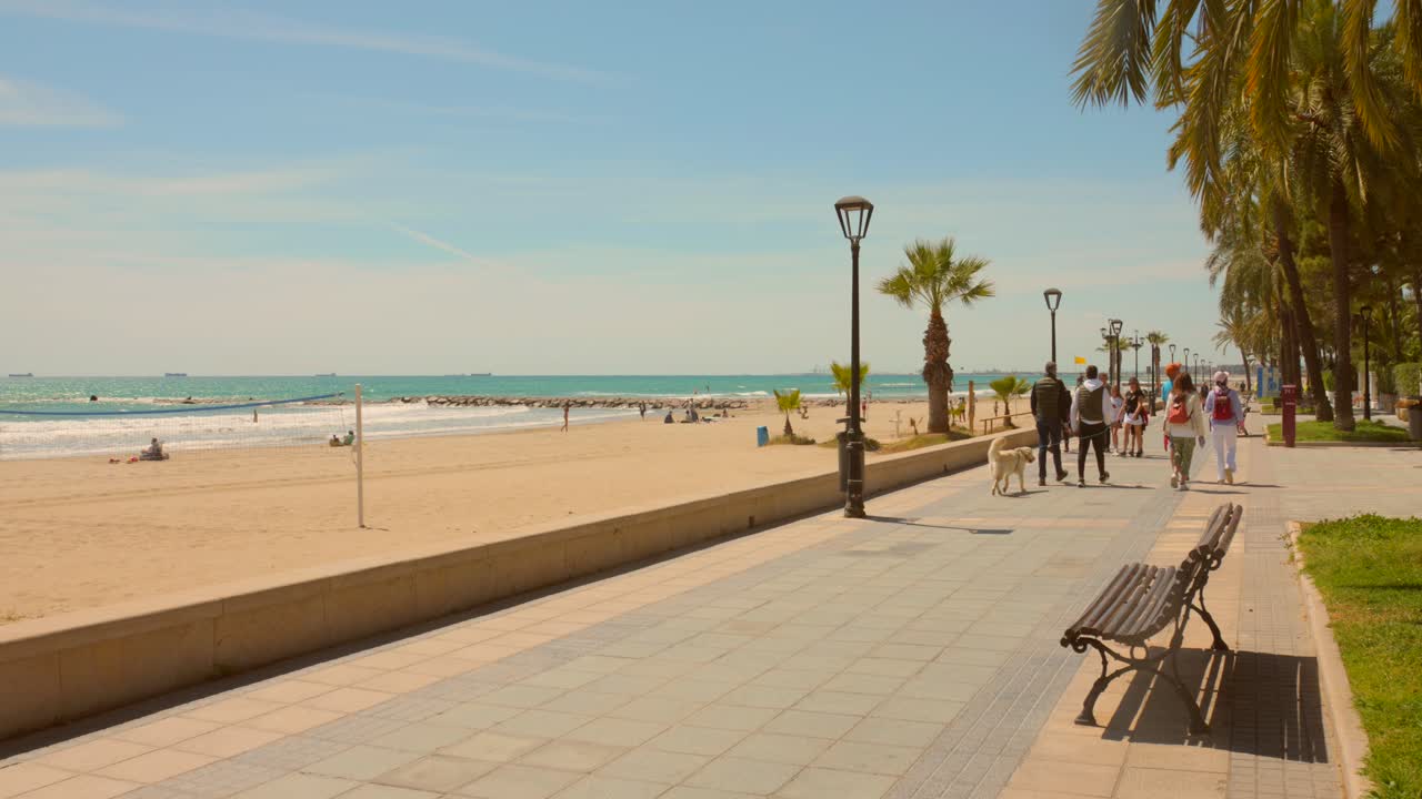 Pan shot of beachside main promenade walkway in Benicassim, Spain on a bright sunny day. 4K.
