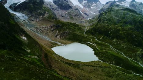 Aerial of glacier lake and winding mountain roads in scenic Swiss Alps landscape