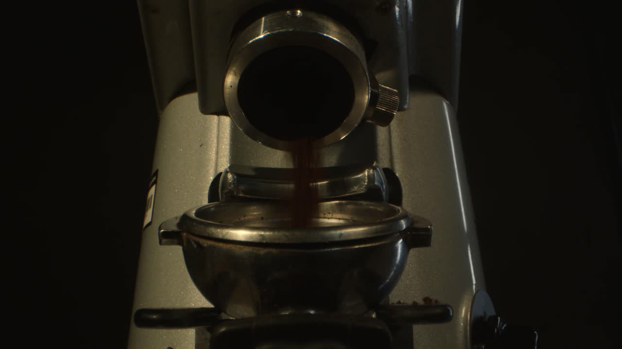 어두운 배경에 맞춰 새로 은 커피를 포타필터로 분배하는 커피 밀러의 클로즈업 이미지