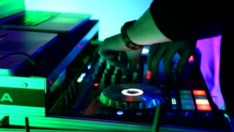 DJ-spinning-a-turn-table-at-a-night-club-with-colorful-lights-in-4K