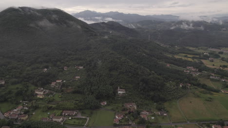 drone timelapse de las nubes que pasan por la cámara en las colinas y montañas en italia en un día gris nublado con pueblos y casas en el suelo entre los campos verdes registro