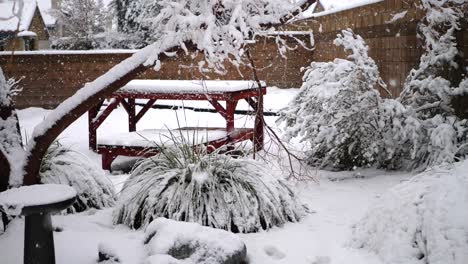 copos de nieve cayendo sobre los árboles en un patio trasero suburbano de américa durante una tormenta de invierno en cámara lenta